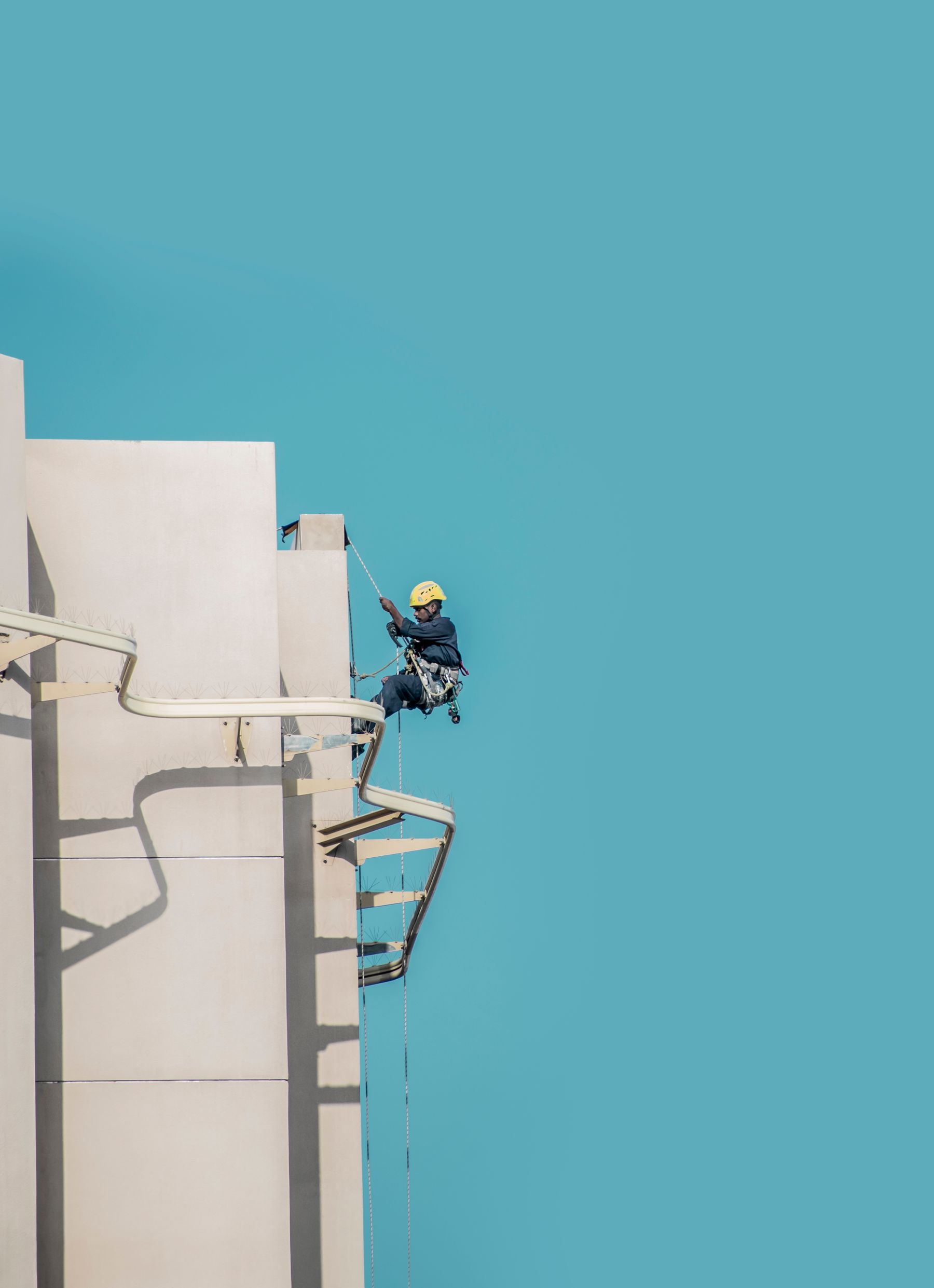 Arbeiter mit Helm und Seilausrüstung an einer hohen Gebäudefassade; Symbolfoto